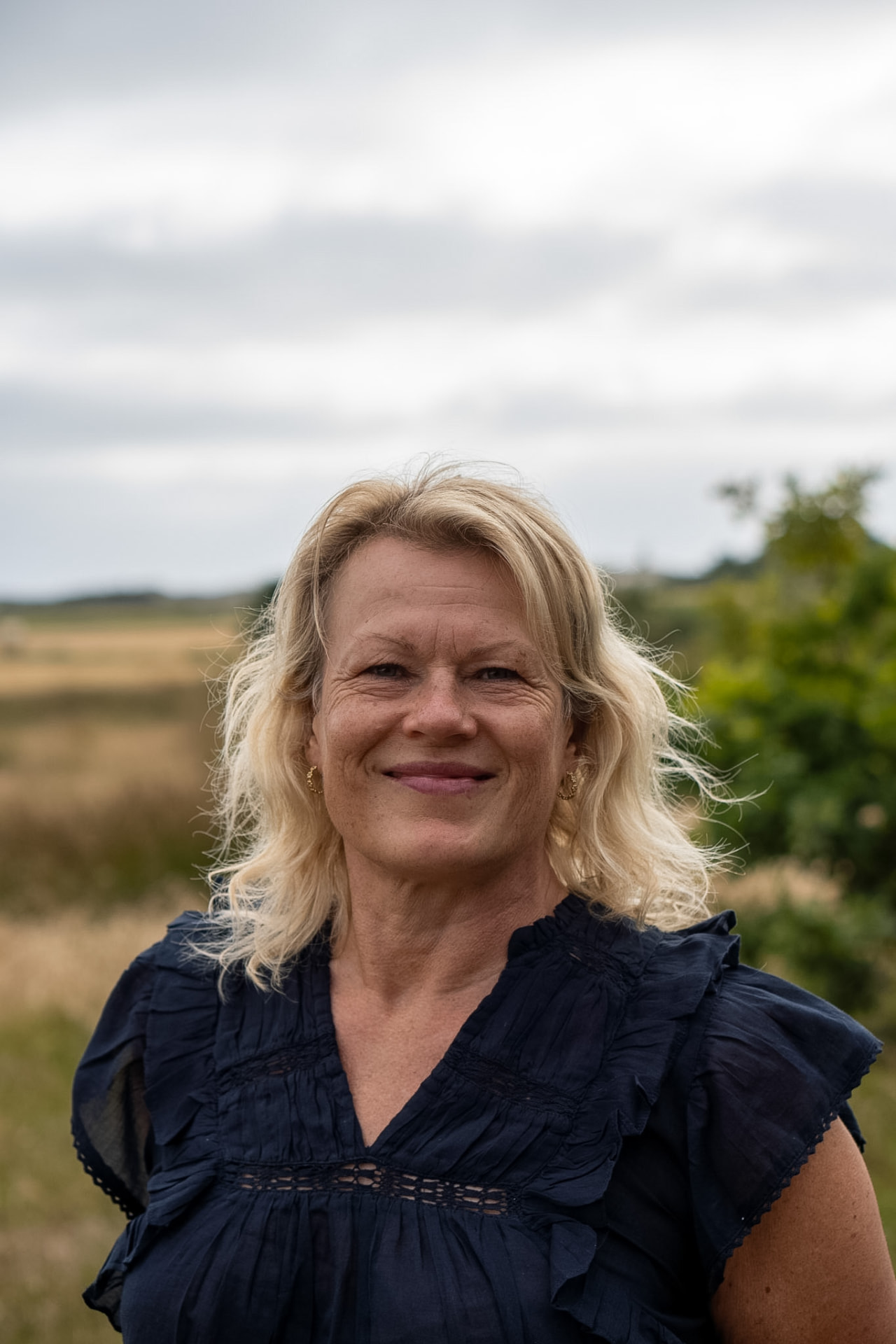 Trine går i skoven med hvidt hus i baggrunden